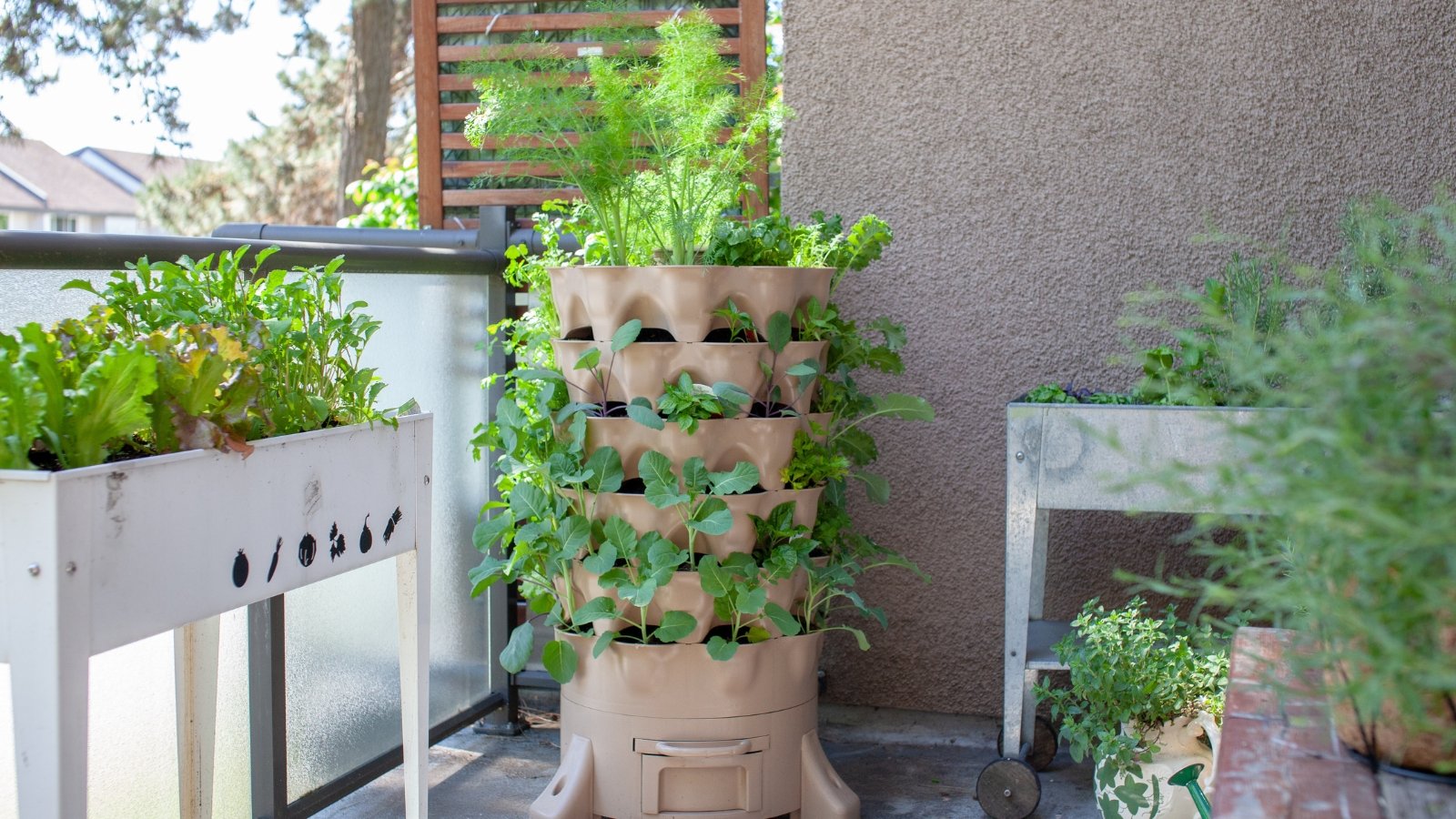 A tall, multi-pocketed brown planter filled with healthy, green foliage on a patio next to a raised garden bed, with large leaves and a variety of small, unripe fruits peeking out from the pockets.