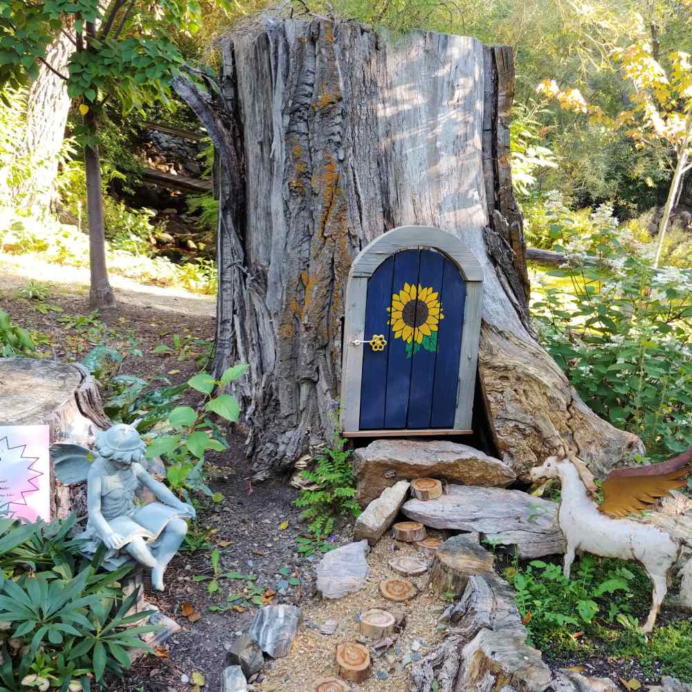 Tree stump with a small door cut into it and unicorn nearby.