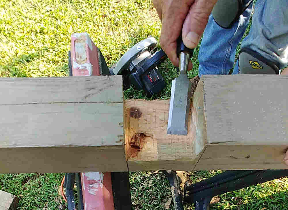 Man using a chisel to smooth a cut out area of a lap joint.