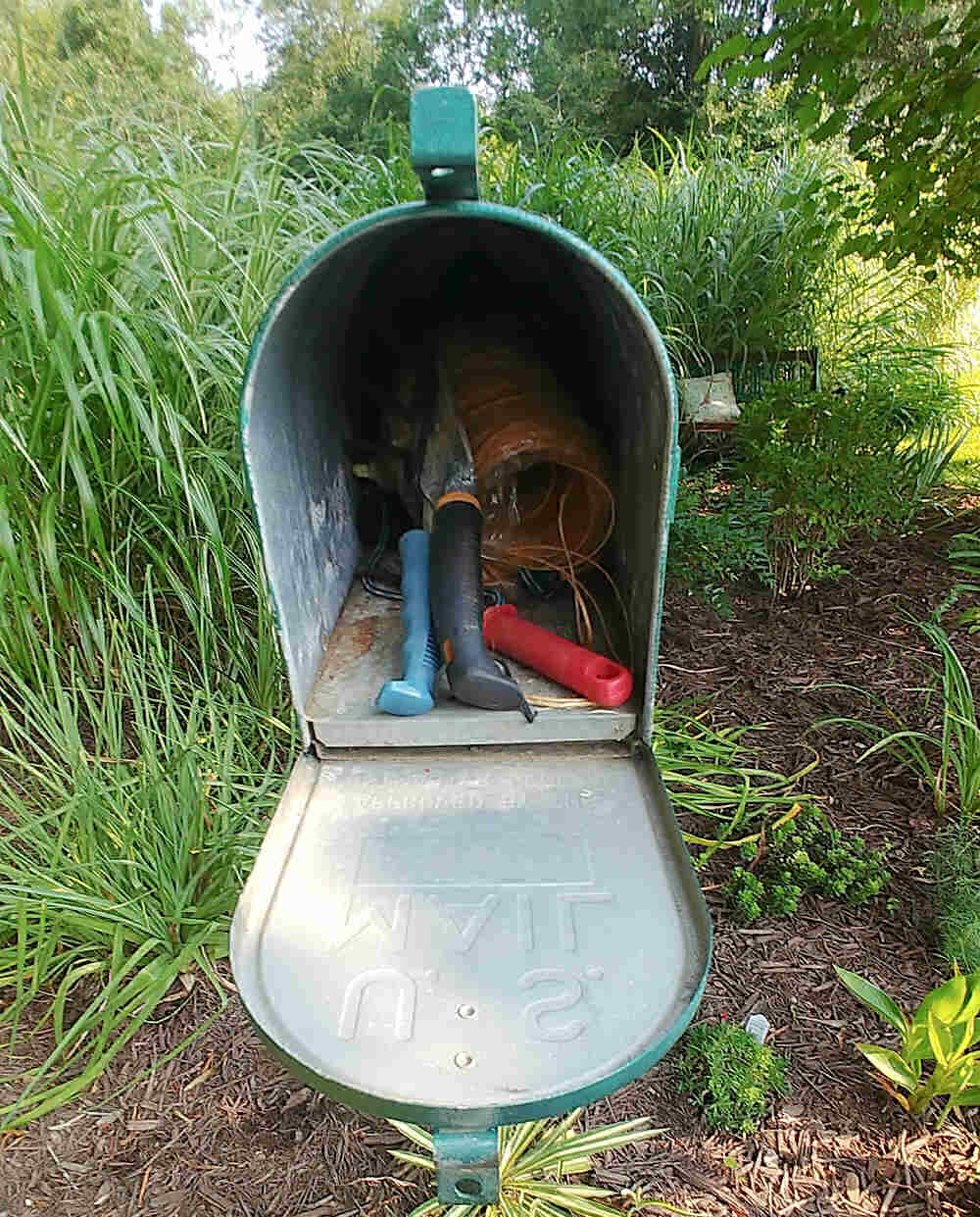 Garden tools stored in a mailbox.