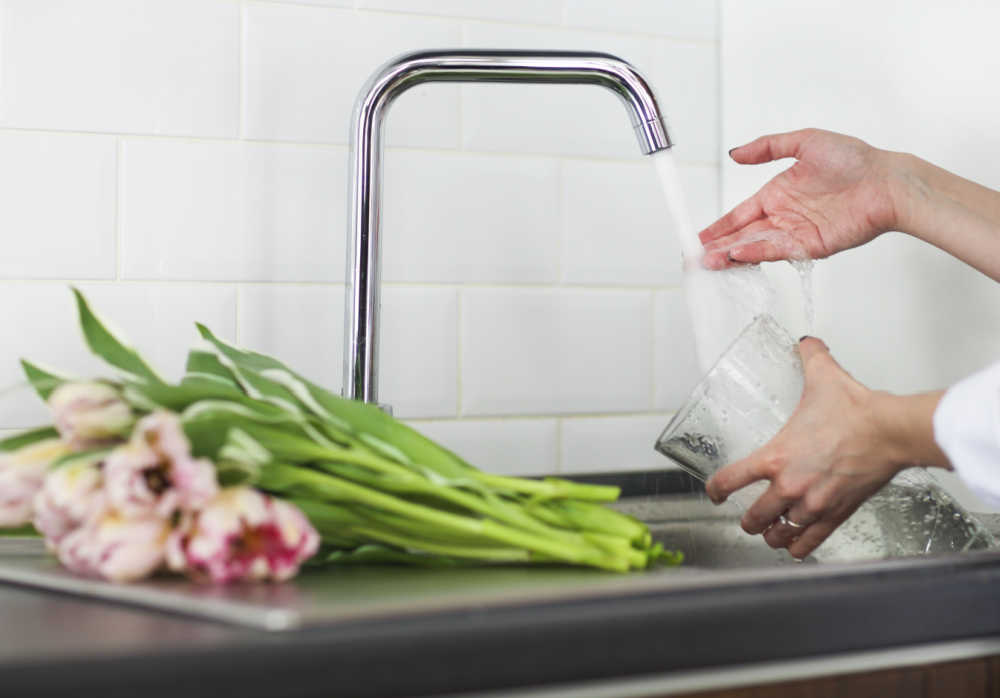 Roses on a counter with woman collecting water in a vase.