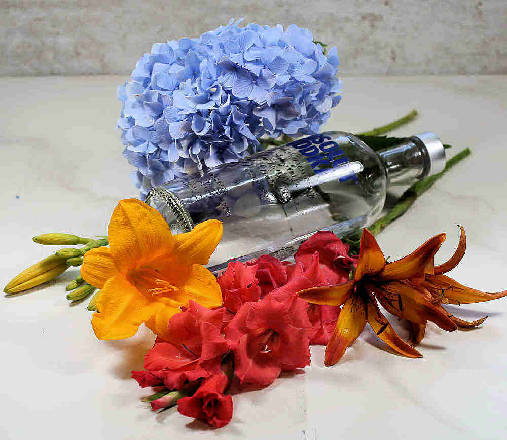 Bottle of vodka with liles, hydrangea and gladiolus.