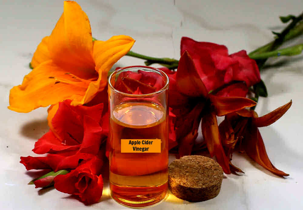 Apple cider vinegar in a container with lilies and gladiolus.