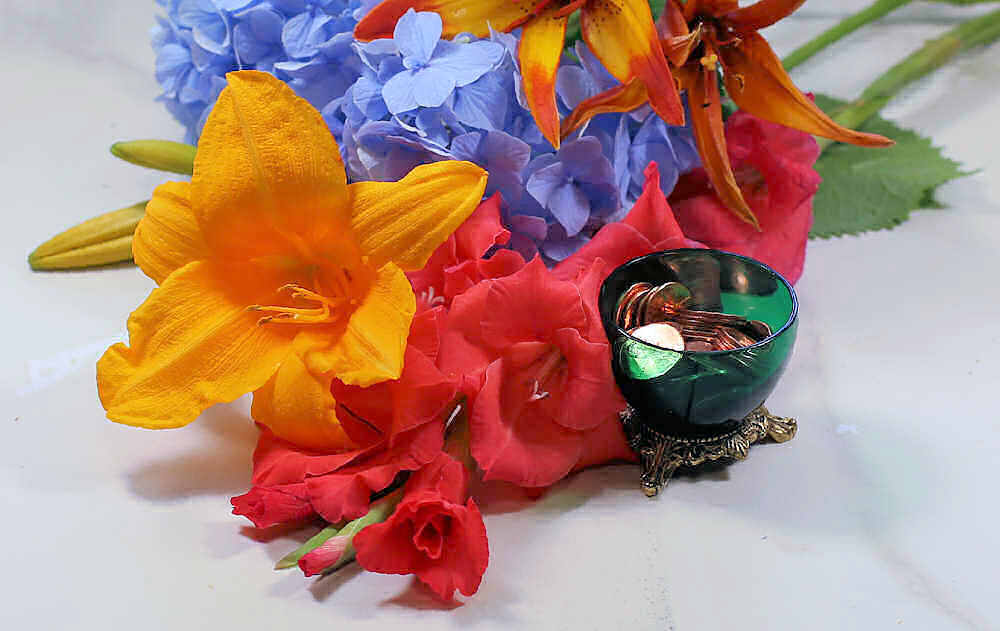 Bowl of copper pennies surrounded by fresh cut flowers.